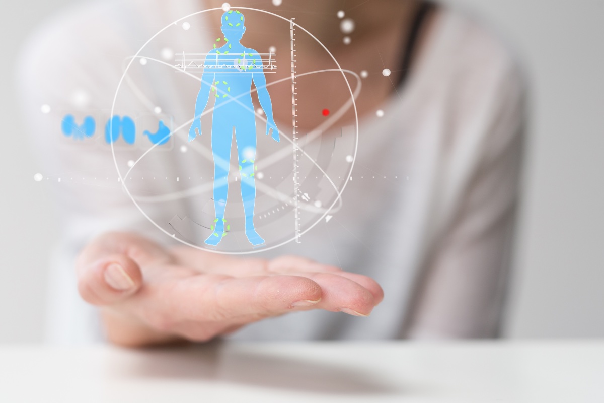 An open hand holding up a holographic full-body health scan — the body shown with data points, a heart trace and organ icons
