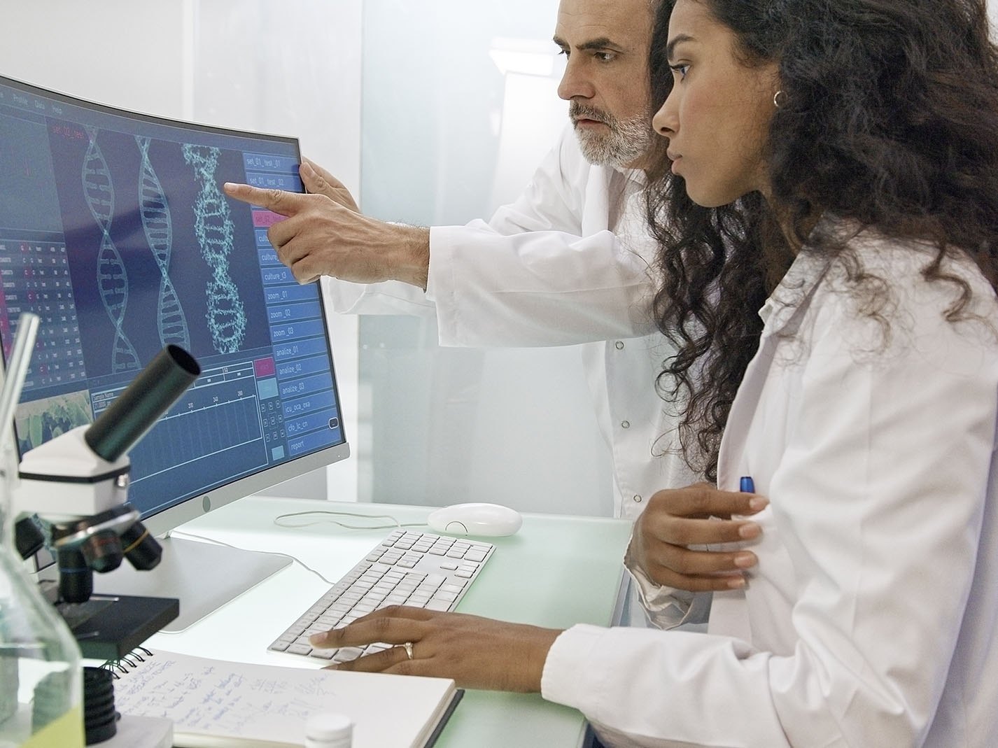 Two scientists reviewing genomic data together on a large laboratory screen